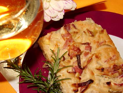 Ein Stück Zwiebelkuchen mit Weinglas und Kräuterdekoration!